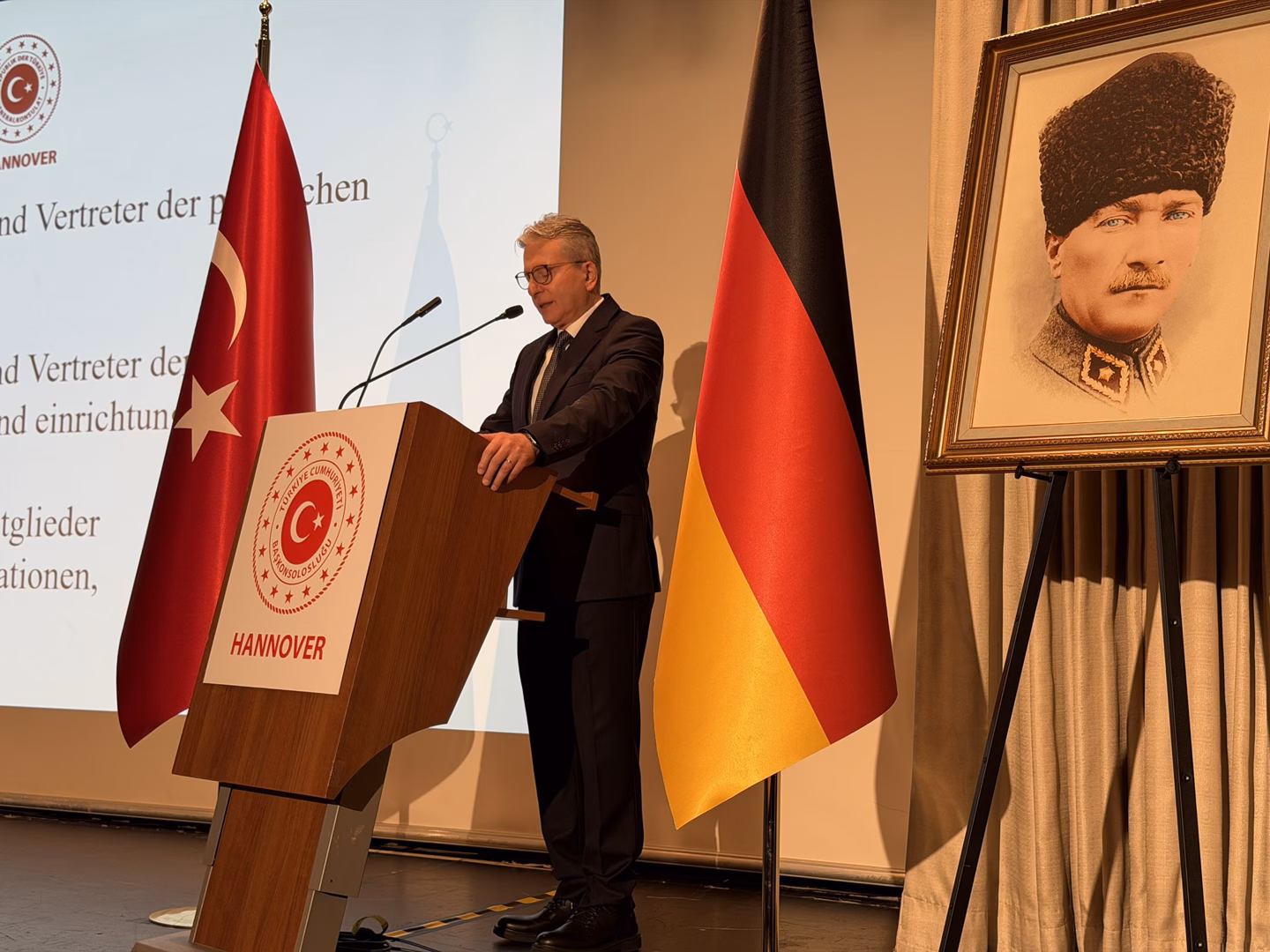 A speech delivered at a podium beside a portrait of Atatürk at the Republic Day reception in Hannover