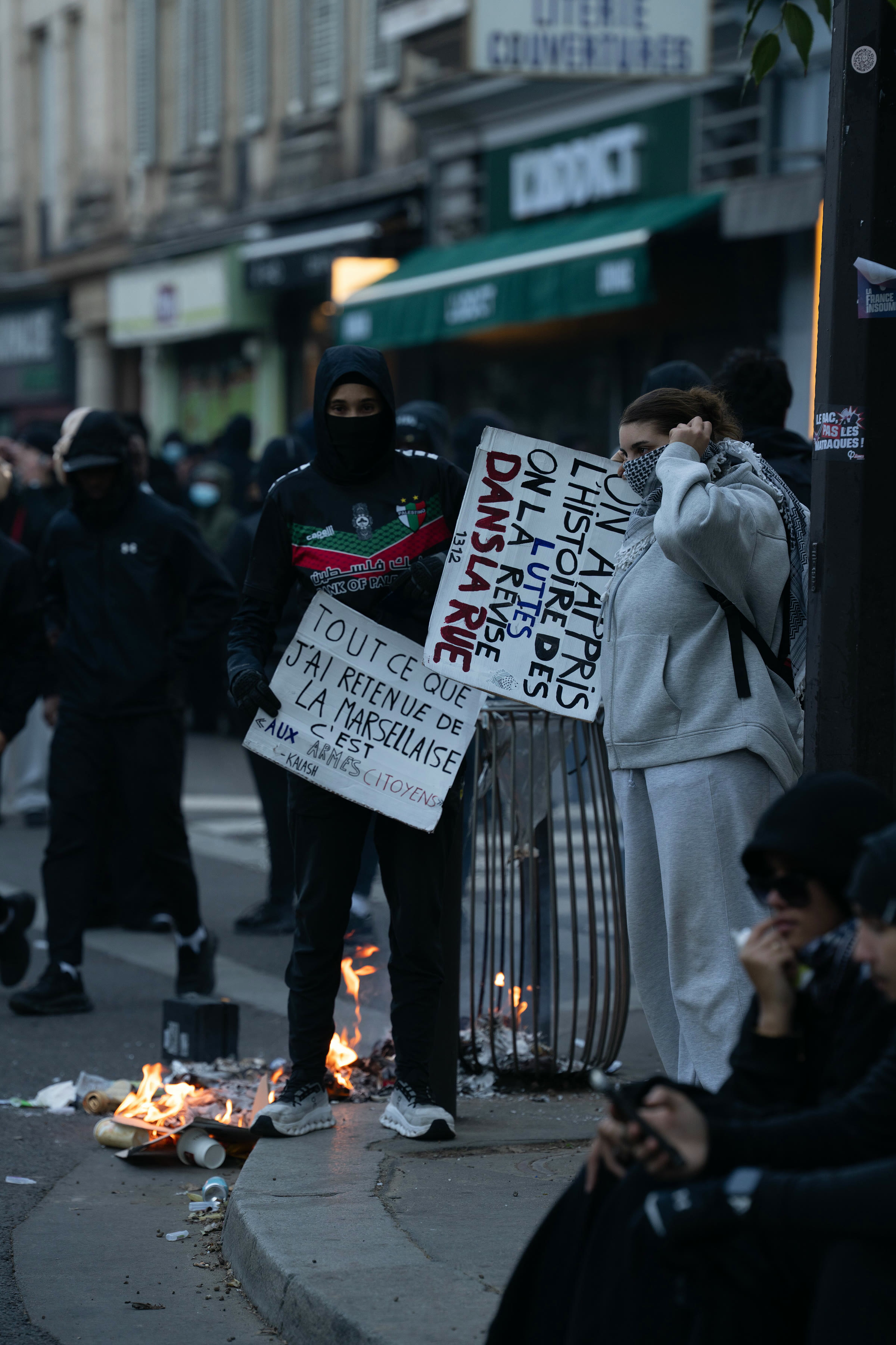 Protesters carrying placards beside a burning vehicle in Paris on Oct. 17