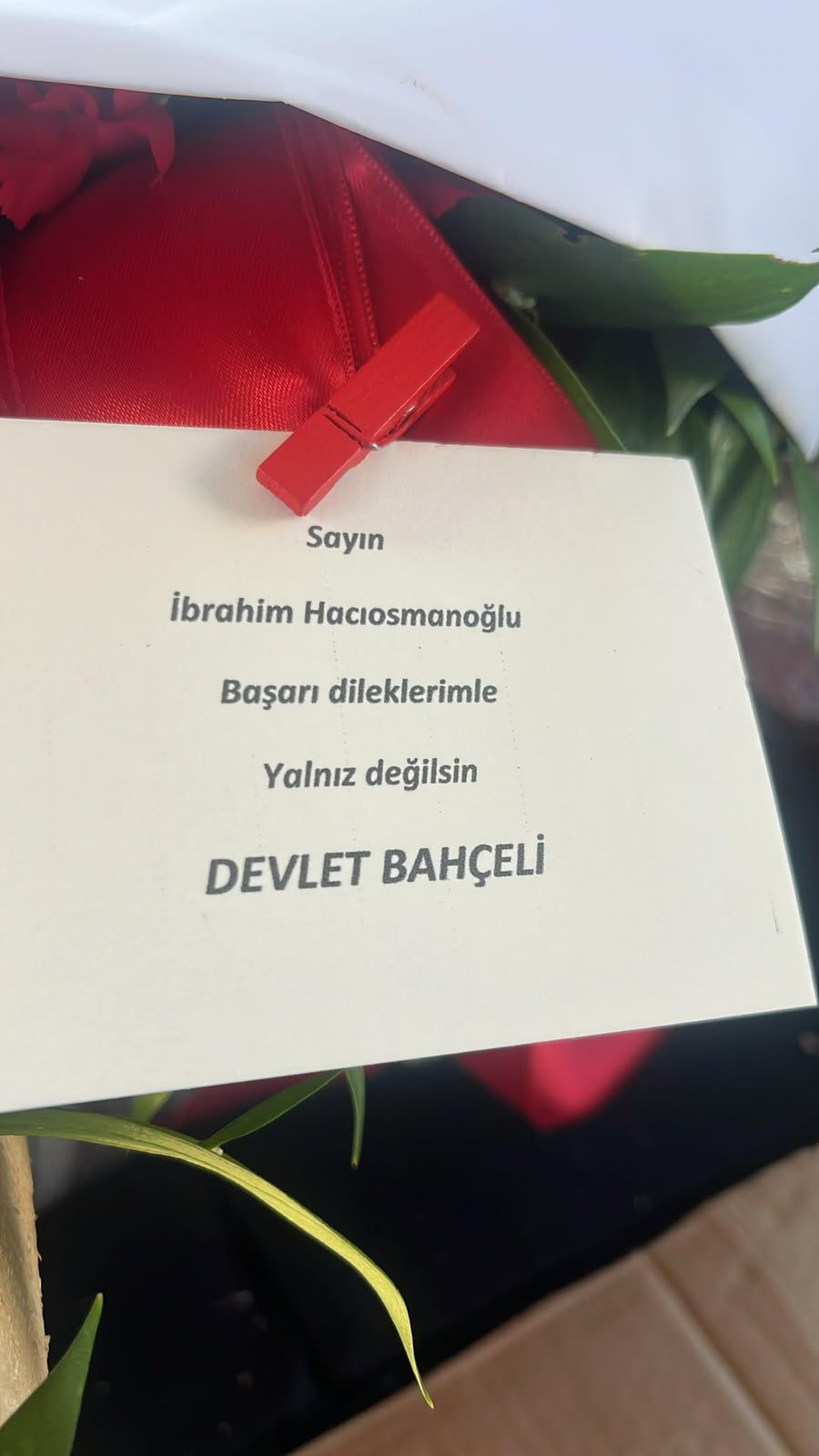 Çiçekteki not: "Sayın İbrahim Hacıosmanoğlu, Başarı dileklerimle, Yalnız değilsin"