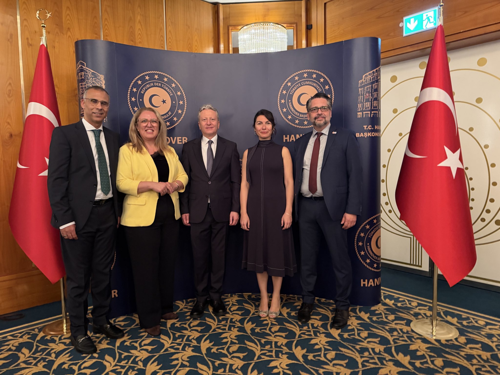 Guests stand in front of the consulate backdrop among Turkish flags